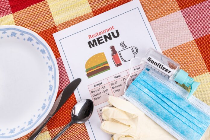 New normal lifestyle with sanitizer, face mask, gloves and disposable menu at restaurant