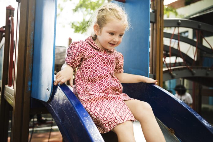 Young girl playing slide in playground