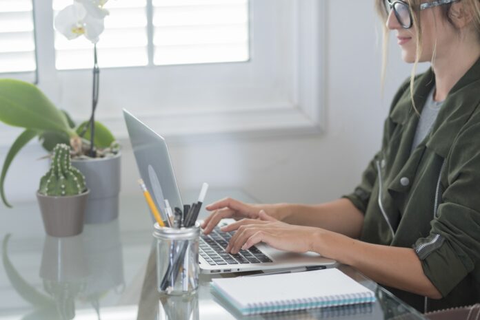 Adult woman type on laptop computer and smile happy for smart working free office home