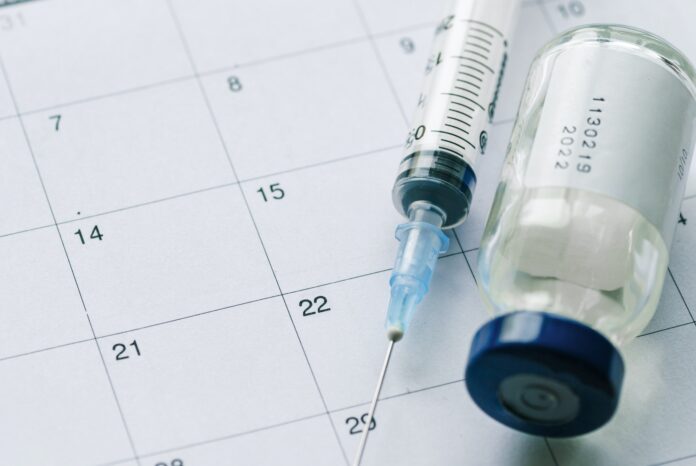 The vial with vaccine and syringe on calendar