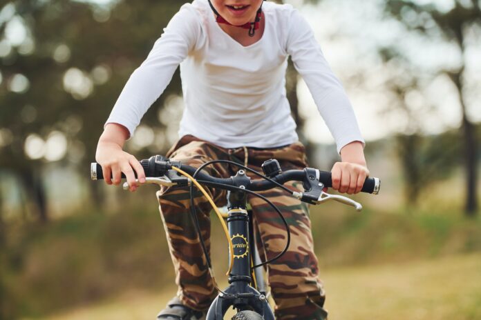 Young boy riding his bike outdoors in the forest at daytime