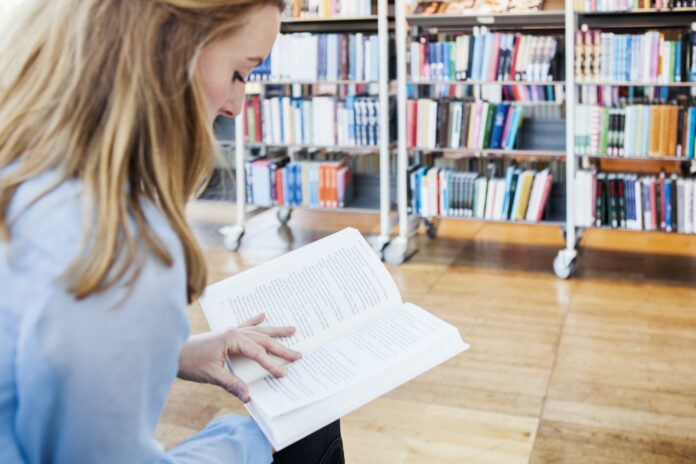 Young woman reading book in library