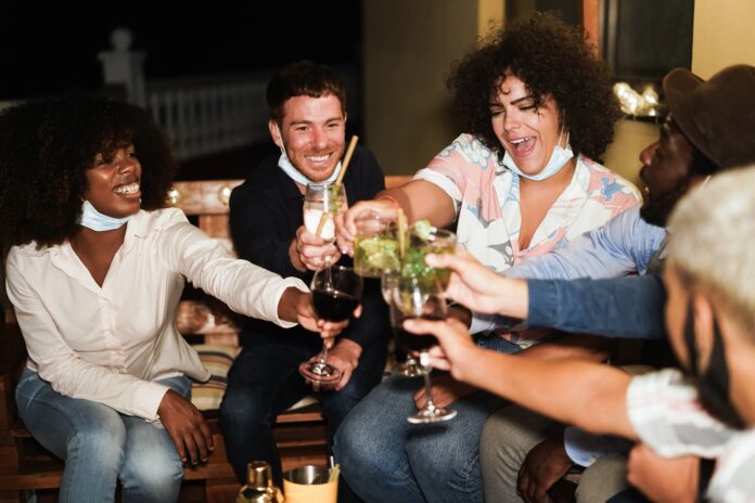 Happy multiracial people having fun drinking cocktails at terrace party during coronavirus outbreak