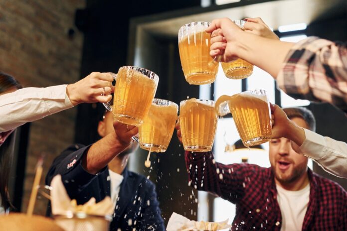 Having conversation. Group of young friends sitting together in bar with beer