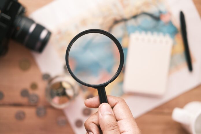 young man using magnifying glass looking something on map