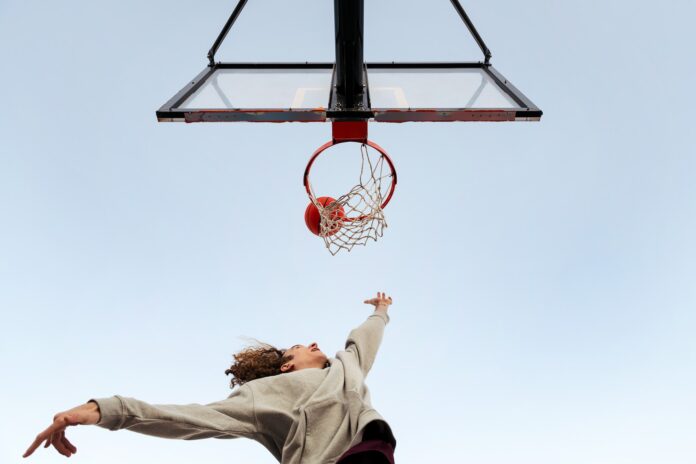 man shooting in a basketball hoop seen from below